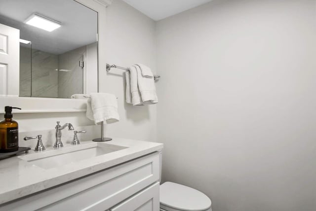 full bath with toilet, vanity, and a walk in shower