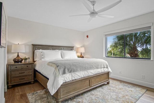 bedroom featuring baseboards, wood finished floors, and ceiling fan
