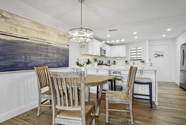 dining room with baseboards, wood finished floors, recessed lighting, and an inviting chandelier