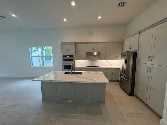 10009 Driftwood Way, Palm Beach Gardens, FL 33412 - kitchen with appliances with stainless steel finishes, a sink, gray cabinets, under cabinet range hood, and recessed lighting