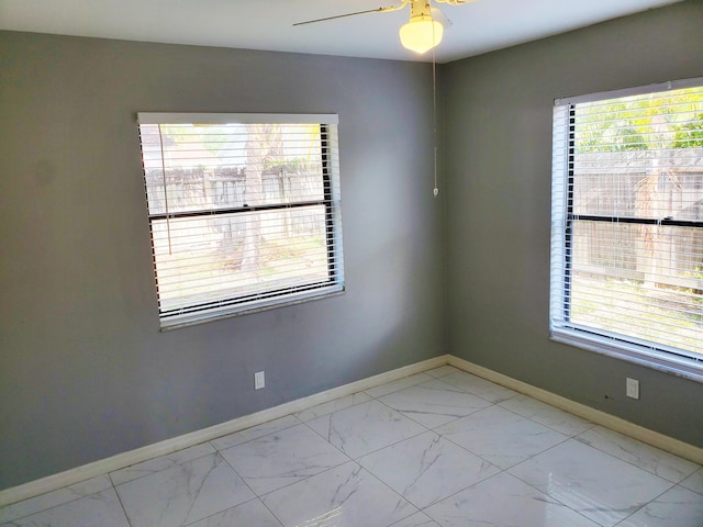 spare room featuring marble finish floor, baseboards, and ceiling fan