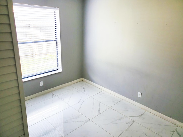 unfurnished room with marble finish floor and baseboards