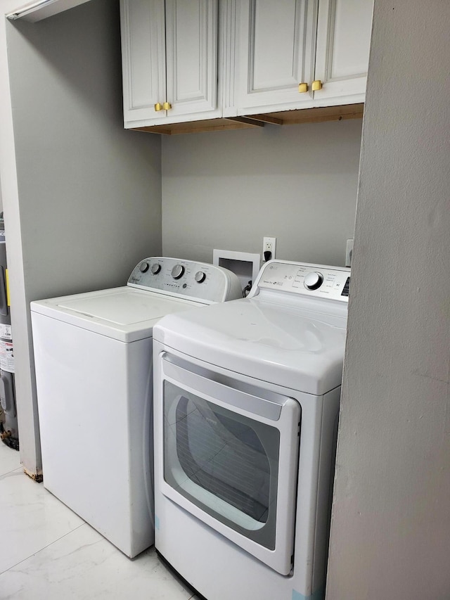 laundry area featuring marble finish floor, independent washer and dryer, and cabinet space
