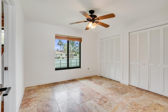 420 SW 128th Ave, Miami, FL 33184 - unfurnished bedroom with baseboards, ceiling fan, stone tile flooring, and two closets