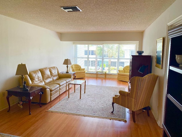 2721 SW 15th St Unit 202, Delray Beach, FL 33445 - living room featuring a textured ceiling, wood finished floors, and healthy amount of natural light