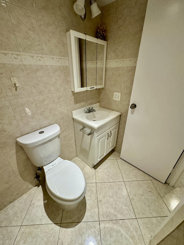 bathroom with vanity, tile patterned floors, toilet, and tile walls