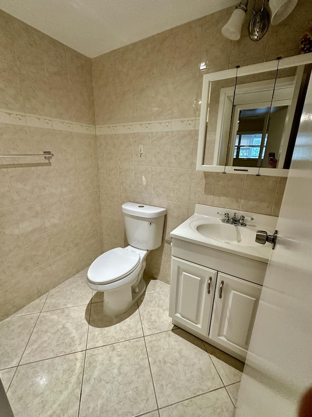 half bathroom featuring tile patterned floors, toilet, tile walls, and vanity
