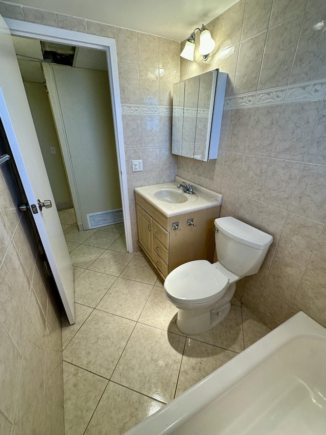 bathroom with tile patterned floors, toilet, tile walls, and vanity
