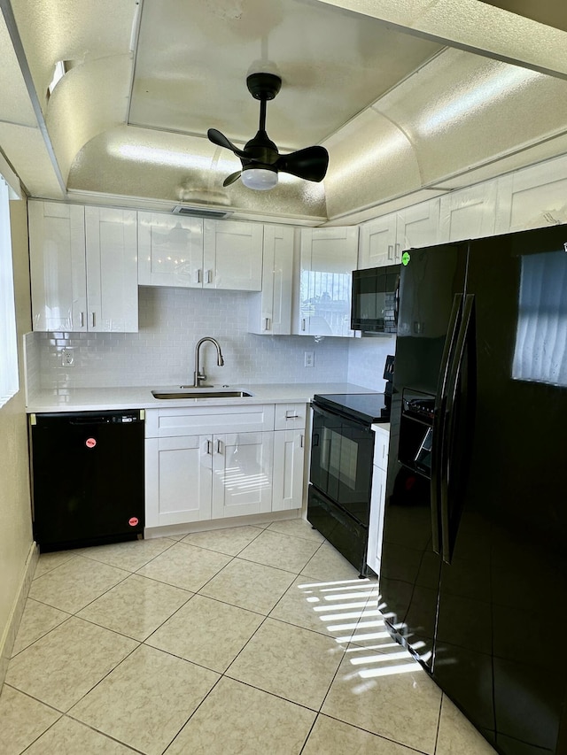 kitchen featuring black appliances, light countertops, light tile patterned floors, white cabinetry, and a sink