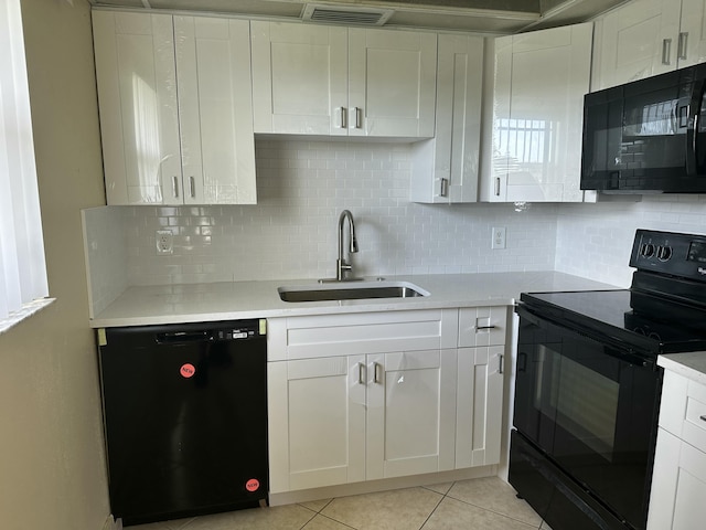 kitchen featuring black appliances, a sink, white cabinetry, light countertops, and light tile patterned floors