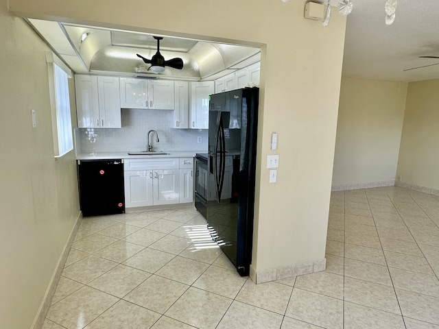 kitchen with black appliances, a sink, a tray ceiling, light tile patterned flooring, and light countertops