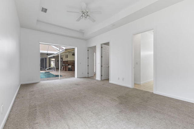 unfurnished room featuring a raised ceiling, visible vents, ceiling fan, baseboards, and carpet floors
