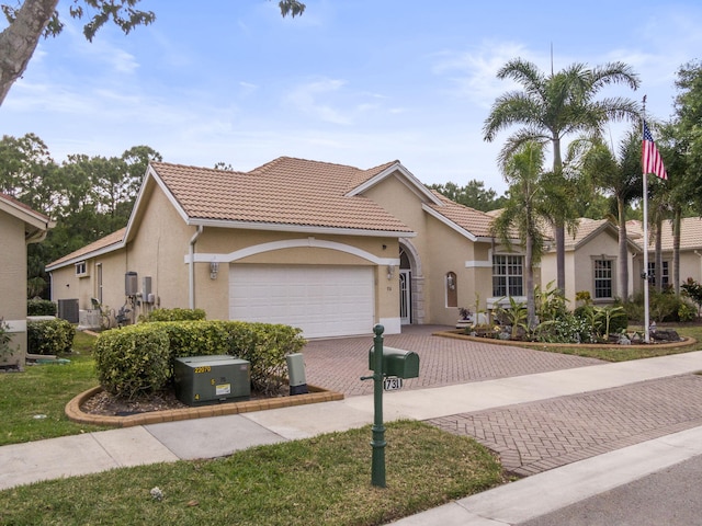 mediterranean / spanish-style home with stucco siding, decorative driveway, a tile roof, and a garage