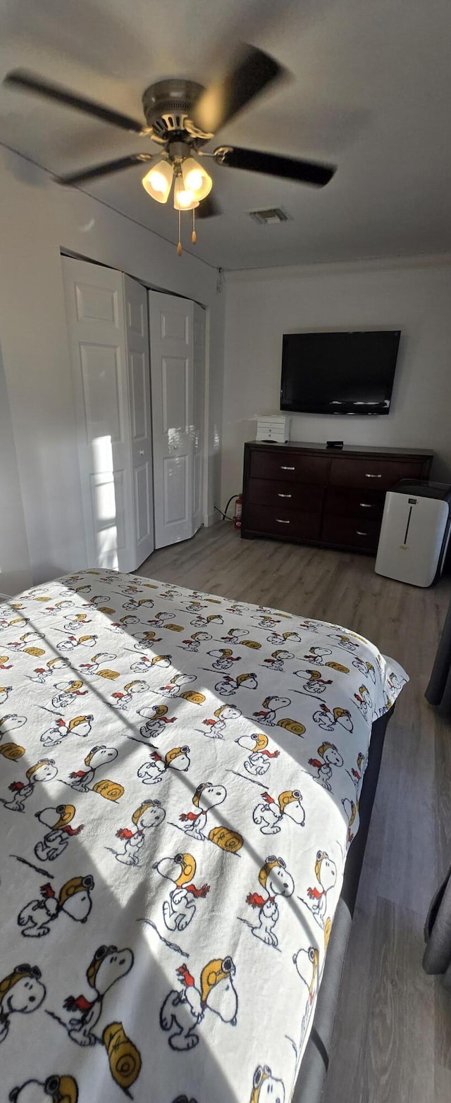 2285 Saratoga Ln, West Palm Beach, FL 33409 - bedroom with light wood-style floors, a closet, ornamental molding, a ceiling fan, and visible vents