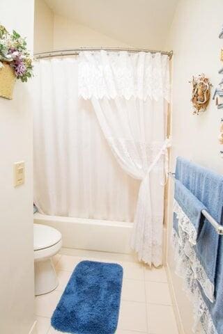 2285 Saratoga Ln, West Palm Beach, FL 33409 - full bathroom featuring toilet, tile patterned floors, and vaulted ceiling