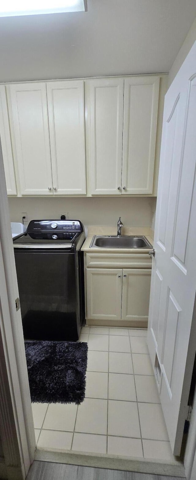 2285 Saratoga Ln, West Palm Beach, FL 33409 - laundry area featuring cabinet space, washer / dryer, light tile patterned flooring, and a sink