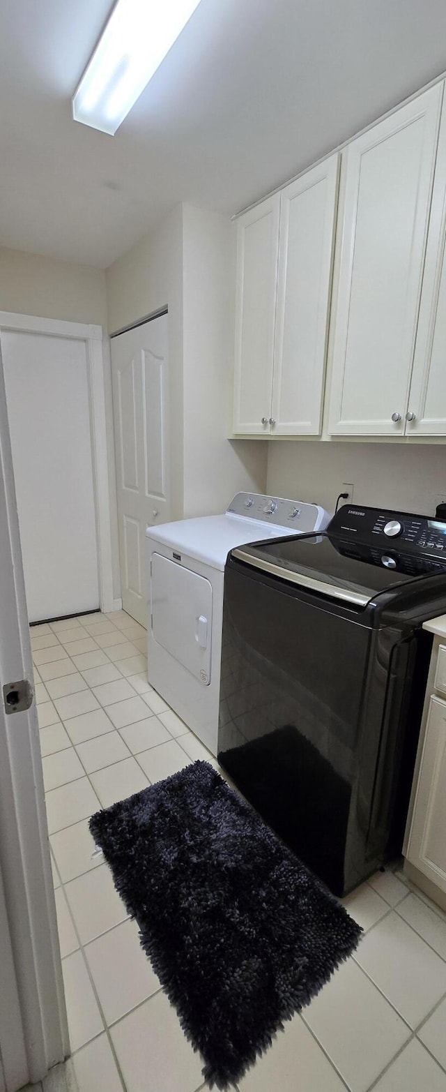 2285 Saratoga Ln, West Palm Beach, FL 33409 - clothes washing area with cabinet space, light tile patterned floors, and separate washer and dryer