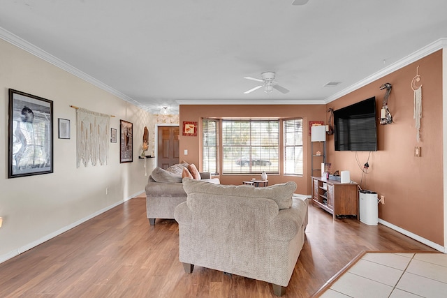 living room featuring light wood-type flooring, crown molding, visible vents, and a ceiling fan