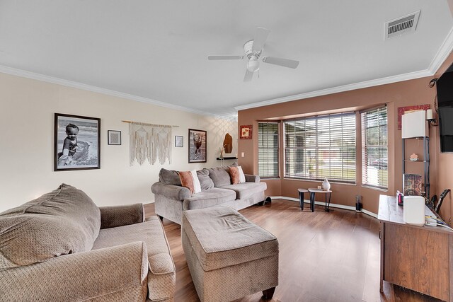 living area featuring wood finished floors, crown molding, ceiling fan, and visible vents