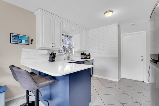 kitchen featuring light countertops, white cabinets, a kitchen breakfast bar, a peninsula, and backsplash