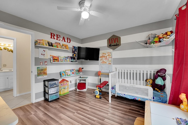 bedroom with baseboards, light wood-type flooring, ensuite bathroom, and a ceiling fan