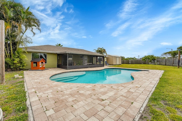 view of pool with a sunroom, a storage unit, an outdoor structure, a yard, and a patio area