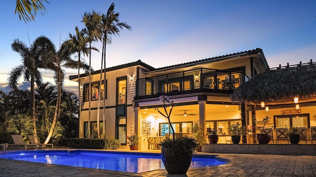 1526 SE 11th St, Deerfield Beach, FL 33441 - back of house at dusk featuring an outdoor pool, a balcony, and a patio