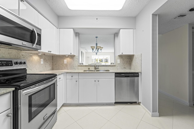 14112 Huntington Pointe Dr Unit 105, Delray Beach, FL 33484 - kitchen featuring a sink, stainless steel appliances, an inviting chandelier, white cabinets, and light tile patterned floors