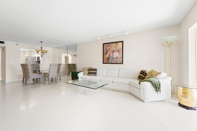 14112 Huntington Pointe Dr Unit 105, Delray Beach, FL 33484 - tiled living area with a notable chandelier, rail lighting, a textured ceiling, and visible vents