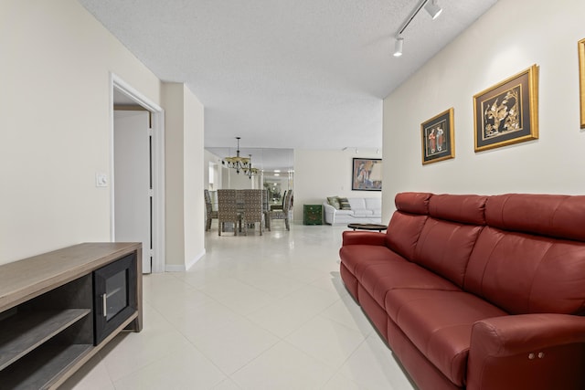 14112 Huntington Pointe Dr Unit 105, Delray Beach, FL 33484 - living room with track lighting, baseboards, an inviting chandelier, light tile patterned flooring, and a textured ceiling