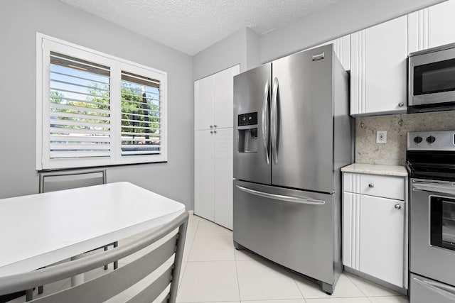 14112 Huntington Pointe Dr Unit 105, Delray Beach, FL 33484 - kitchen featuring white cabinetry, appliances with stainless steel finishes, light countertops, light tile patterned floors, and decorative backsplash