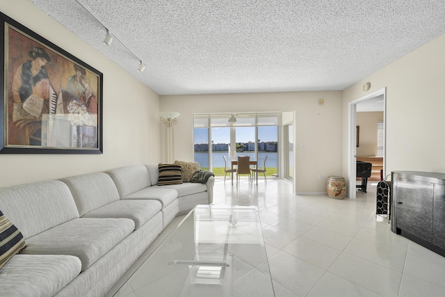 14112 Huntington Pointe Dr Unit 105, Delray Beach, FL 33484 - living room with a water view, a textured ceiling, light tile patterned flooring, and rail lighting