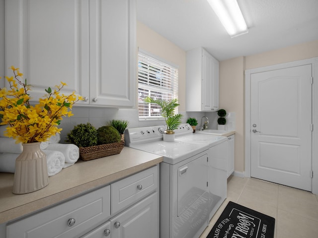clothes washing area featuring cabinet space, light tile patterned floors, a sink, and separate washer and dryer