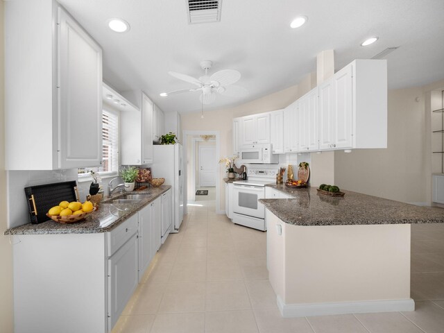 kitchen with a sink, white appliances, a peninsula, white cabinetry, and visible vents