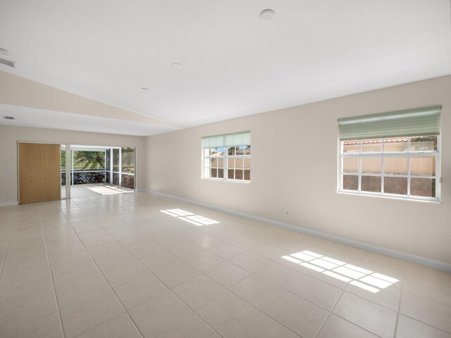 unfurnished room featuring baseboards, lofted ceiling, visible vents, and light tile patterned floors