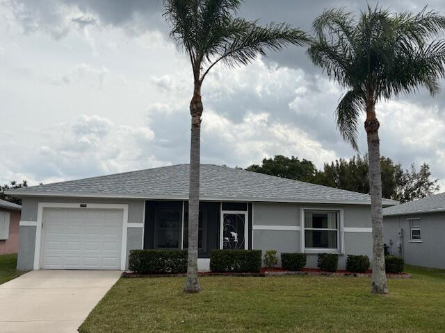 ranch-style house with a garage, a front yard, and stucco siding