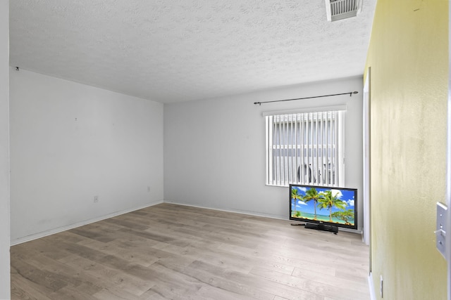 unfurnished living room with wood finished floors, a textured ceiling, and visible vents
