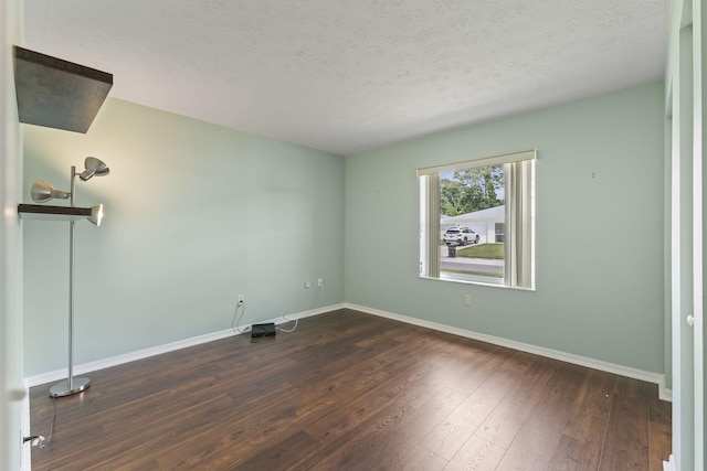 empty room with dark wood finished floors, baseboards, and a textured ceiling