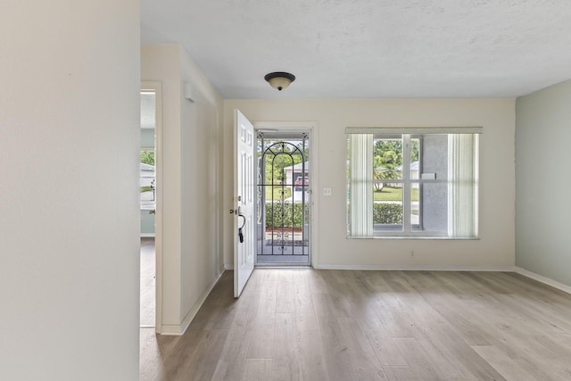 foyer featuring baseboards, wood finished floors, and a textured ceiling