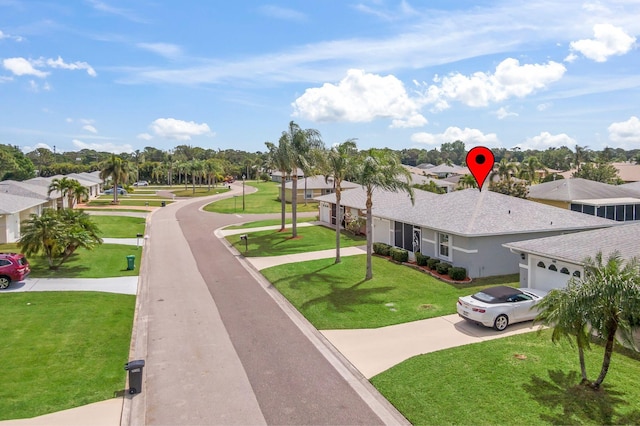 view of home's community with a residential view, driveway, a garage, and a yard