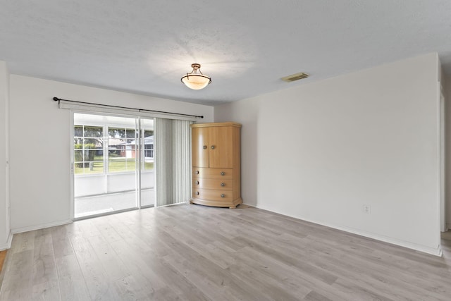 unfurnished room featuring visible vents, a textured ceiling, baseboards, and light wood-type flooring
