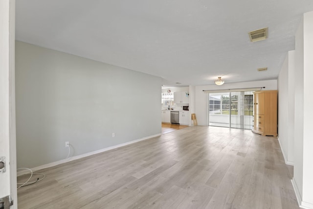 unfurnished living room with baseboards, visible vents, and light wood-style floors