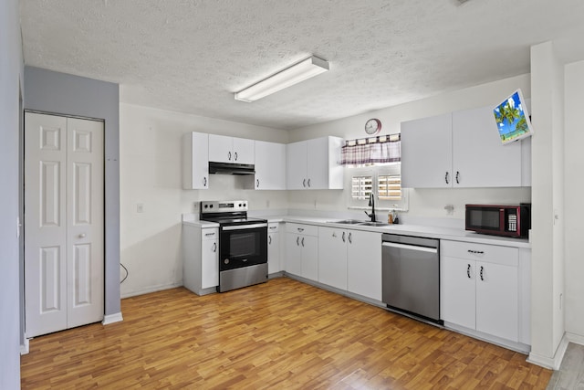 kitchen with light countertops, a sink, stainless steel appliances, and under cabinet range hood
