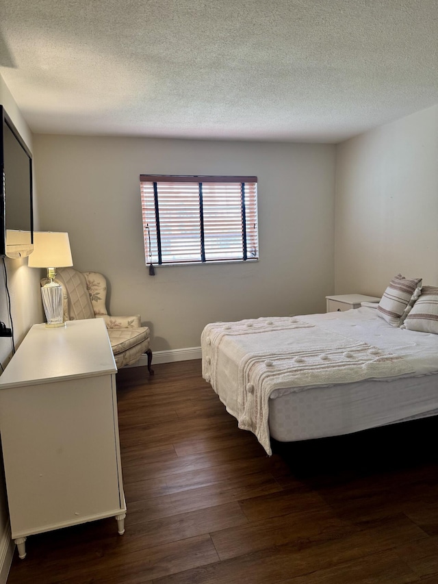 bedroom featuring a textured ceiling, baseboards, and dark wood-style flooring