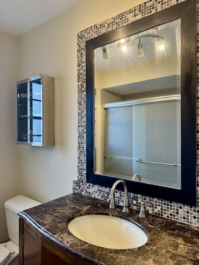 bathroom featuring toilet, vanity, and decorative backsplash