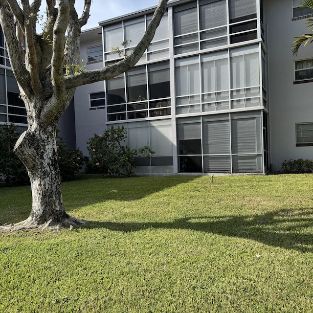 rear view of house with stucco siding and a yard