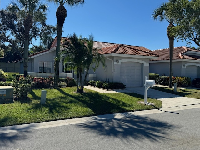 mediterranean / spanish-style home featuring a tile roof, concrete driveway, a front yard, stucco siding, and an attached garage