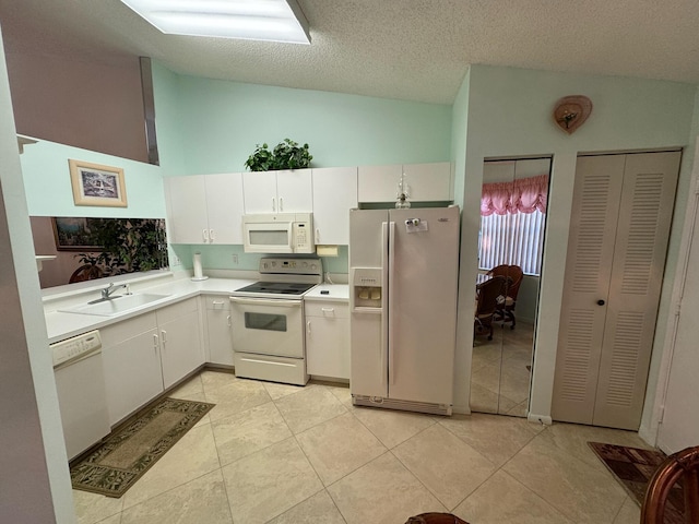 kitchen with white appliances, light countertops, lofted ceiling, and a sink