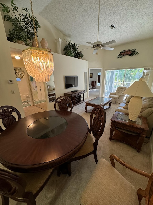 dining space with visible vents, high vaulted ceiling, a textured ceiling, light carpet, and ceiling fan with notable chandelier