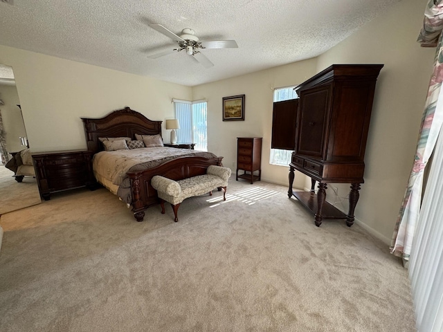 bedroom featuring baseboards, light carpet, a textured ceiling, and ceiling fan